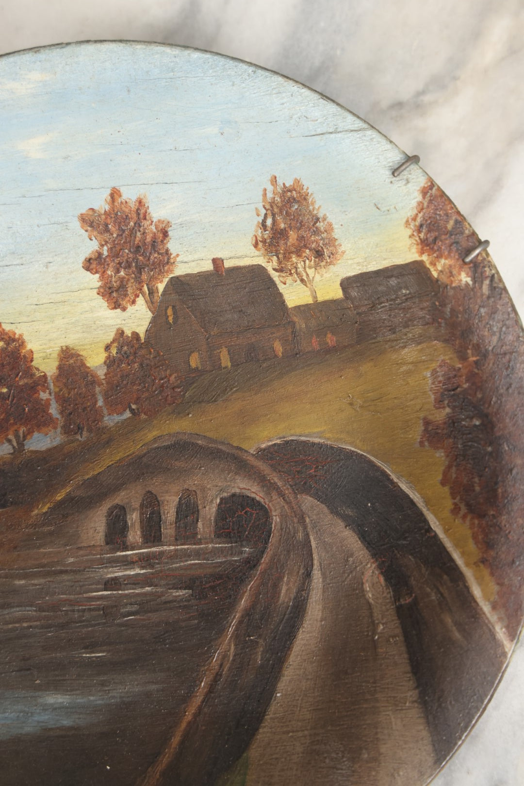 Lot 039 - Antique Hand Painted Wooden Plate, Landscape Scene With A Bridge Over A River, Foliage, With Plate Hanger