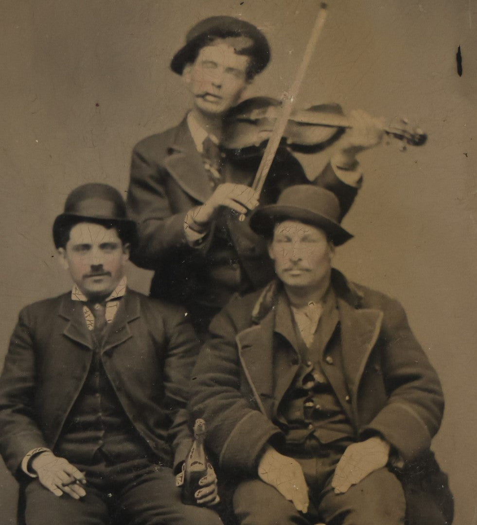 Lot 064 - Single Antique Tintype Photograph Of Three Men, One Playing Violin And Smoking, One Smoking And Drinking