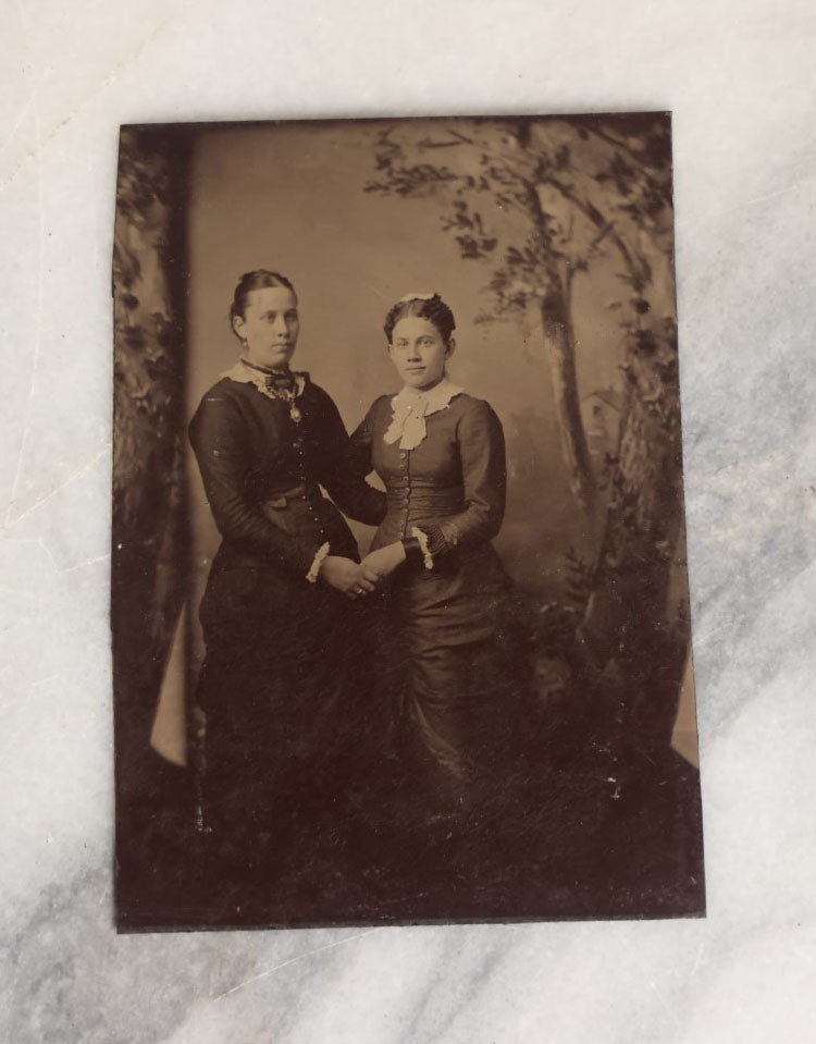 Lot 068 - Single Antique Tintype Photograph Of Two Women Posing Holding Hands, Embracing, With Trees In Back Drop