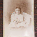 Lot 055 - Antique Cabinet Card Photograph Of A Toddler, Young Boy Or Girl, Holding Doll, With Nervous Smile, Wide Eyes, L.P. Ogden, Successor To B.F. Ogden Photographer, Massachusetts, New York