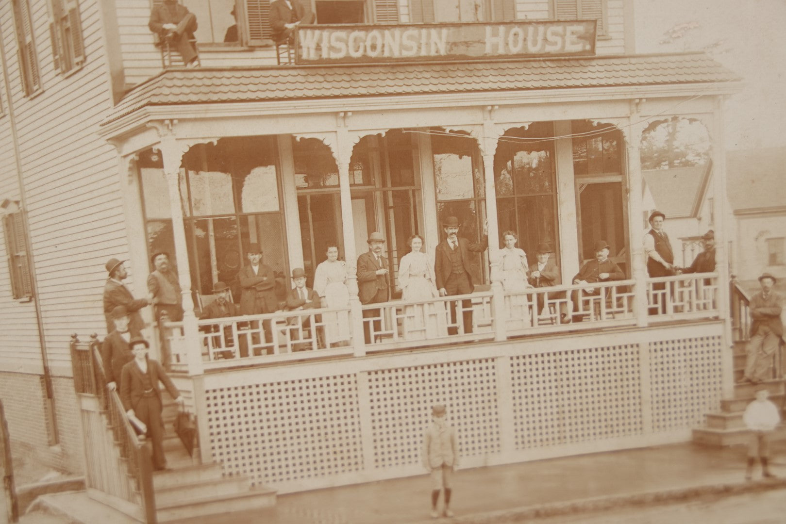 Lot 063 - Antique Boarded Photograph Of Wisconsin House, Possible Inn, With Many Men, Women, And Children On Porch, On Roof