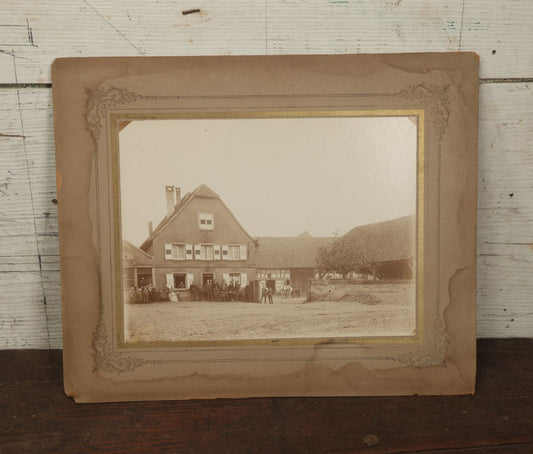 Lot 135 - Antique Boarded Photo Of A Large Group Of Photo Outside Of A Building With A Trade Sign Hanging From It, Horse Drawn Carriage In The Background, Men, Women, And Children, Unknown Location