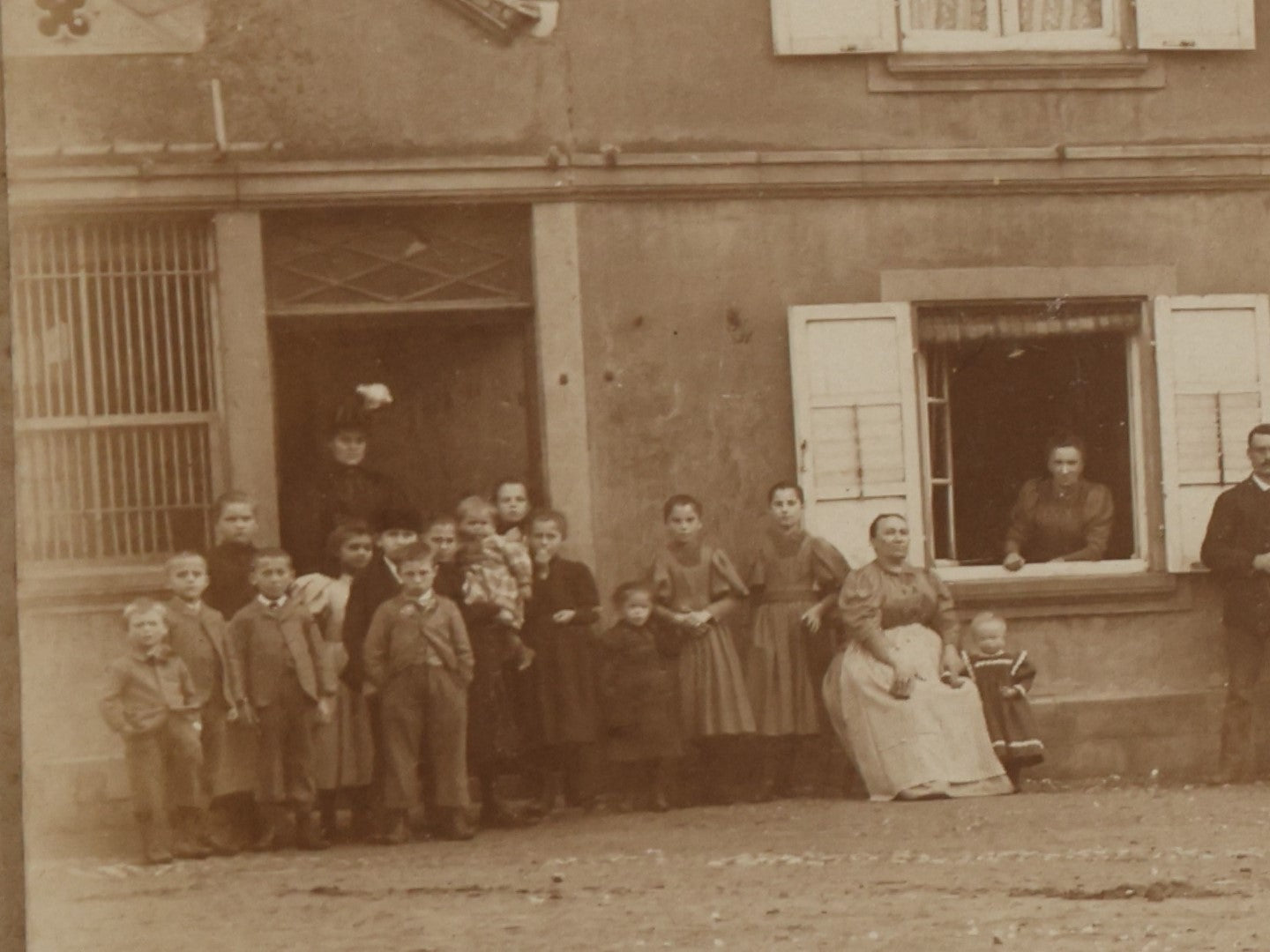 Lot 135 - Antique Boarded Photo Of A Large Group Of Photo Outside Of A Building With A Trade Sign Hanging From It, Horse Drawn Carriage In The Background, Men, Women, And Children, Unknown Location