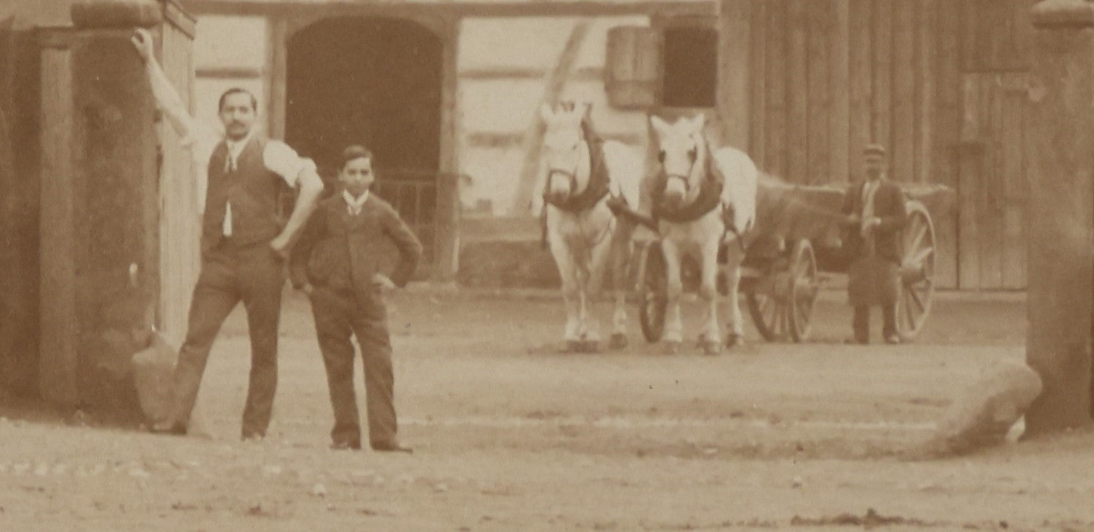 Lot 135 - Antique Boarded Photo Of A Large Group Of Photo Outside Of A Building With A Trade Sign Hanging From It, Horse Drawn Carriage In The Background, Men, Women, And Children, Unknown Location