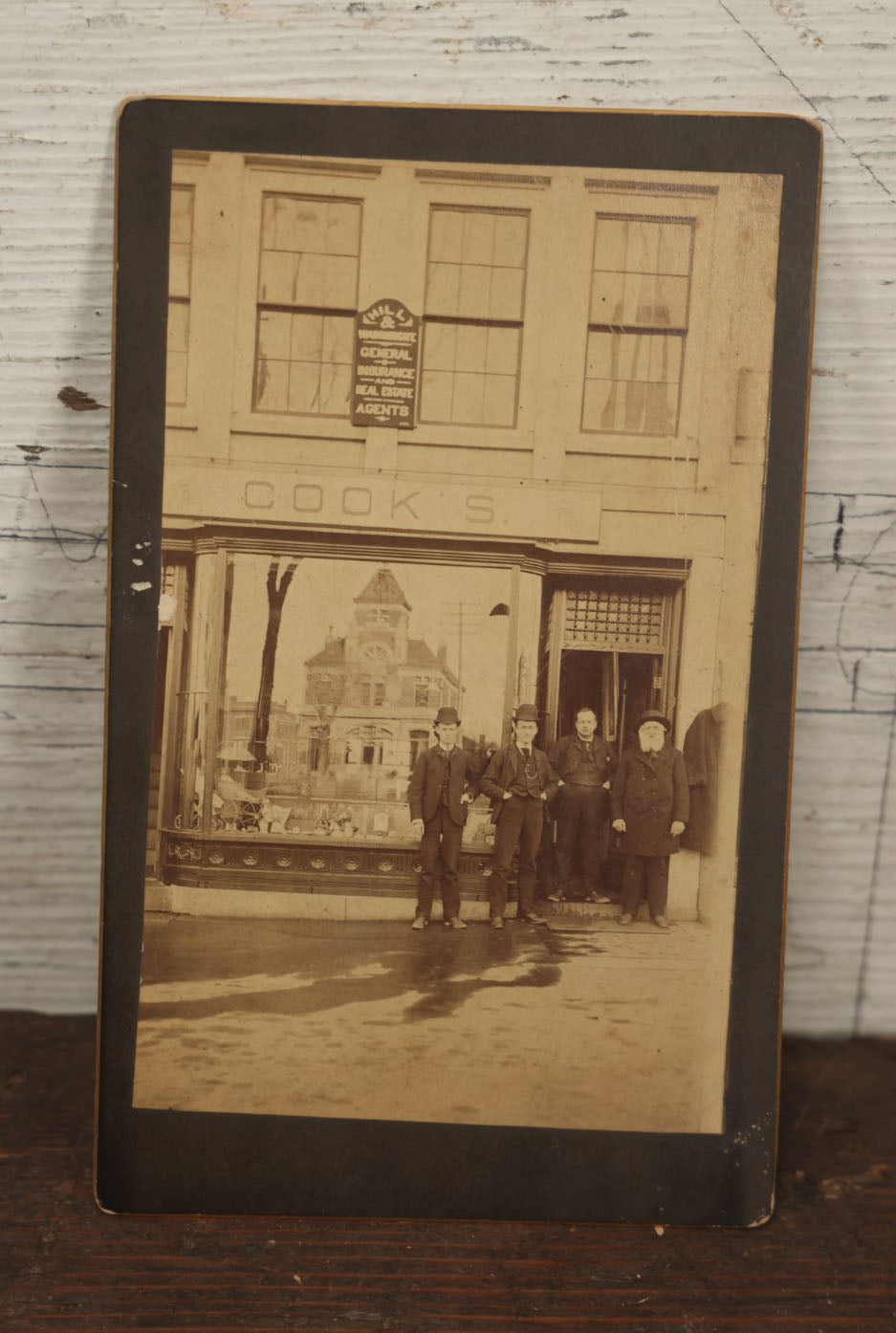 Lot 051 - Antique Cabinet Card Occupational Photograph Of Four Men Outside Of A Commercial Building Store Front, Sign Says "Cook's", Real Estate Sign, Building In Window Reflection, Men Id'd On Back