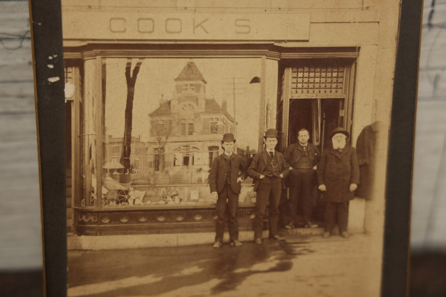 Lot 051 - Antique Cabinet Card Occupational Photograph Of Four Men Outside Of A Commercial Building Store Front, Sign Says "Cook's", Real Estate Sign, Building In Window Reflection, Men Id'd On Back