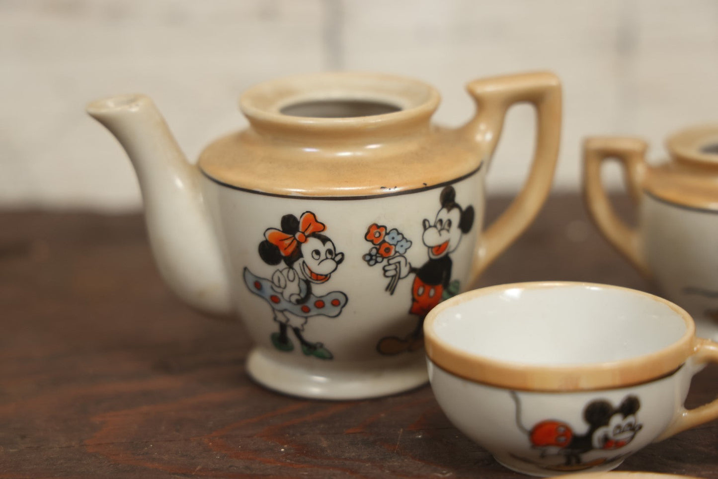 Lot 056 - Grouping Of Eight Vintage Hand Painted Mickey And Minnie Mouse Disney Tea Set Pieces Including Teapot, Creamer, Sugar Bowl, Cups, And Plates, Note Various Chips, Wear, Made In Occupied Japan, Walt Disney Productions