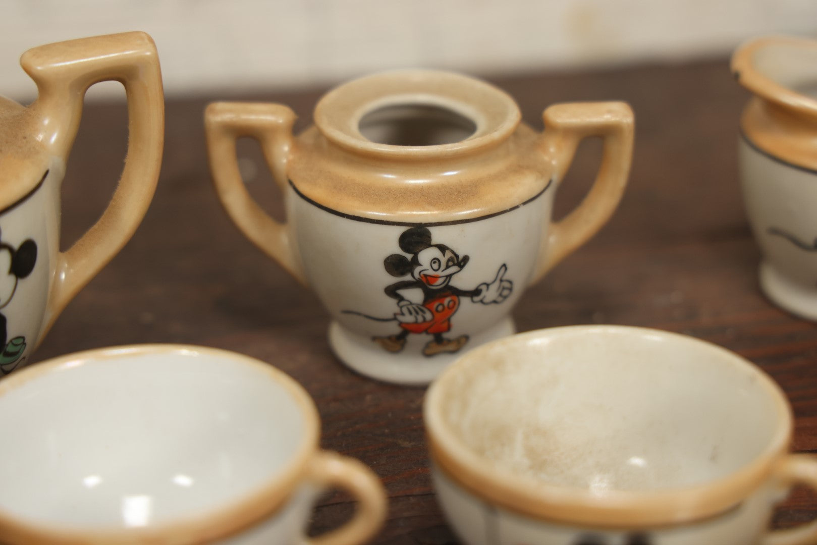 Lot 056 - Grouping Of Eight Vintage Hand Painted Mickey And Minnie Mouse Disney Tea Set Pieces Including Teapot, Creamer, Sugar Bowl, Cups, And Plates, Note Various Chips, Wear, Made In Occupied Japan, Walt Disney Productions