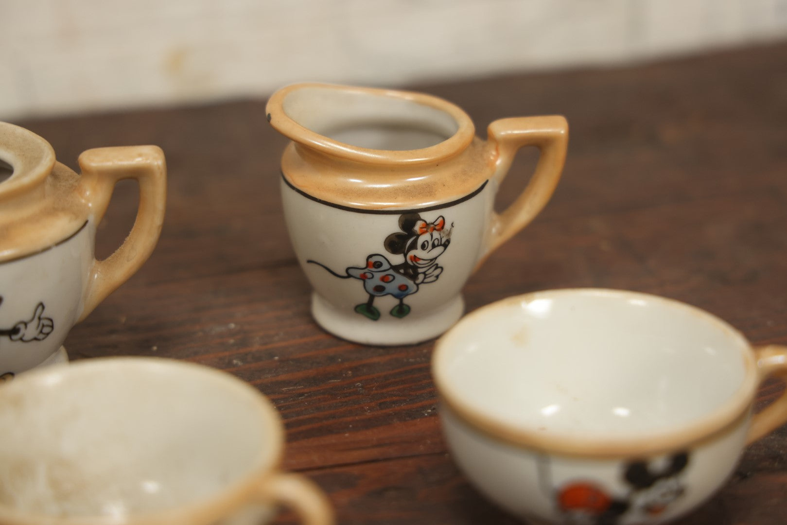 Lot 056 - Grouping Of Eight Vintage Hand Painted Mickey And Minnie Mouse Disney Tea Set Pieces Including Teapot, Creamer, Sugar Bowl, Cups, And Plates, Note Various Chips, Wear, Made In Occupied Japan, Walt Disney Productions