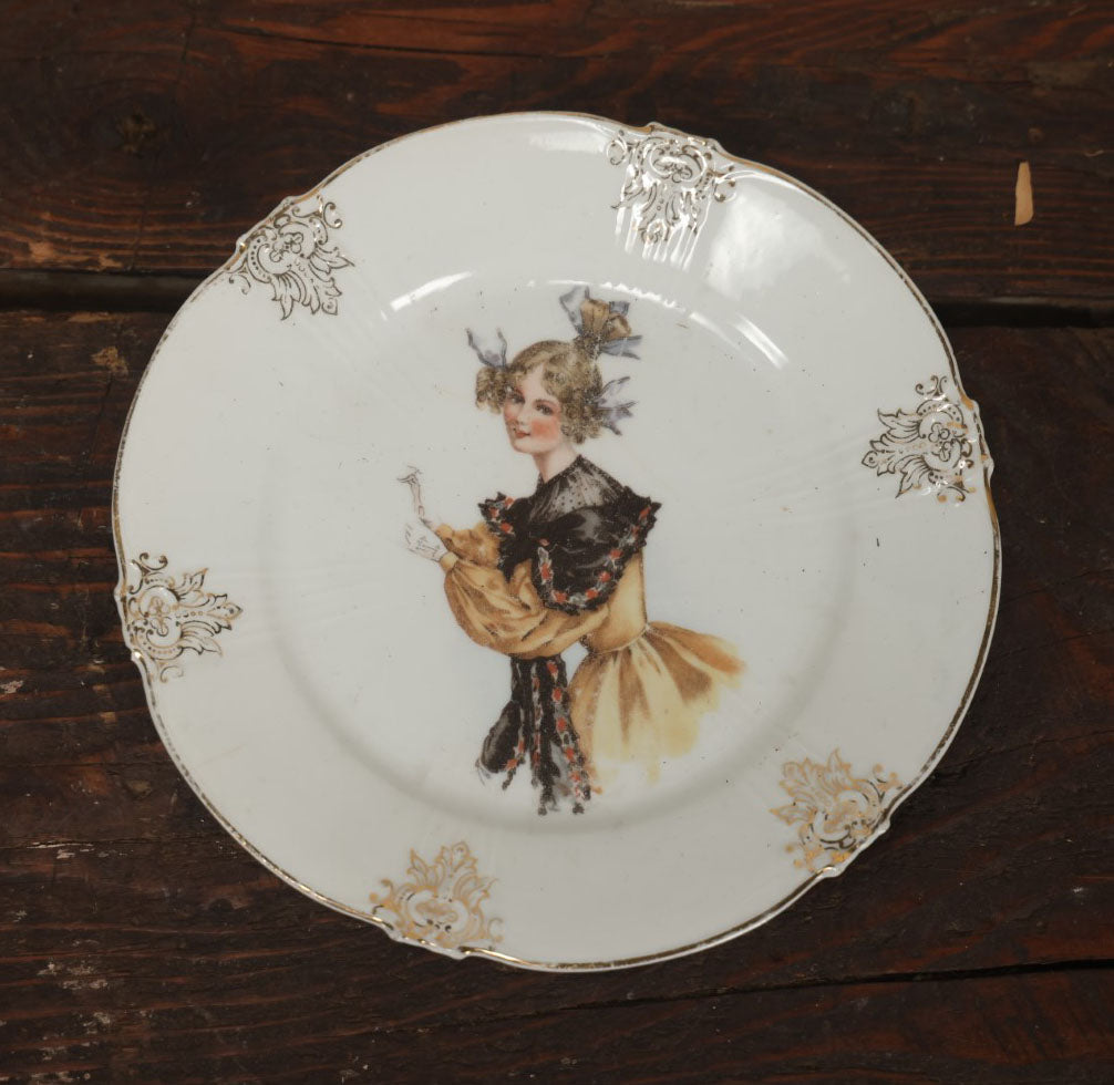 Lot 061 - Antique Porcelain Transferware Plate, With Woman In Yellow Dress, Black Shawl, Funky Hair, White Gloves