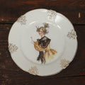Lot 061 - Antique Porcelain Transferware Plate, With Woman In Yellow Dress, Black Shawl, Funky Hair, White Gloves
