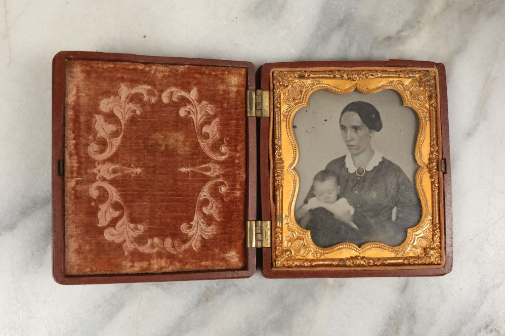 Lot 003 - Antique 1/6th Plate Ambrotype Of Woman With Sleeping Baby In Her Arms, Gold Painted Jewelry On Image, In Thermoplastic Case