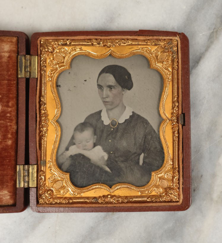 Lot 003 - Antique 1/6th Plate Ambrotype Of Woman With Sleeping Baby In Her Arms, Gold Painted Jewelry On Image, In Thermoplastic Case