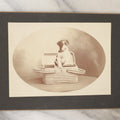 Lot 019 - Antique Boarded Photo Of A Small Black And White Puppy In A Picnic Basket