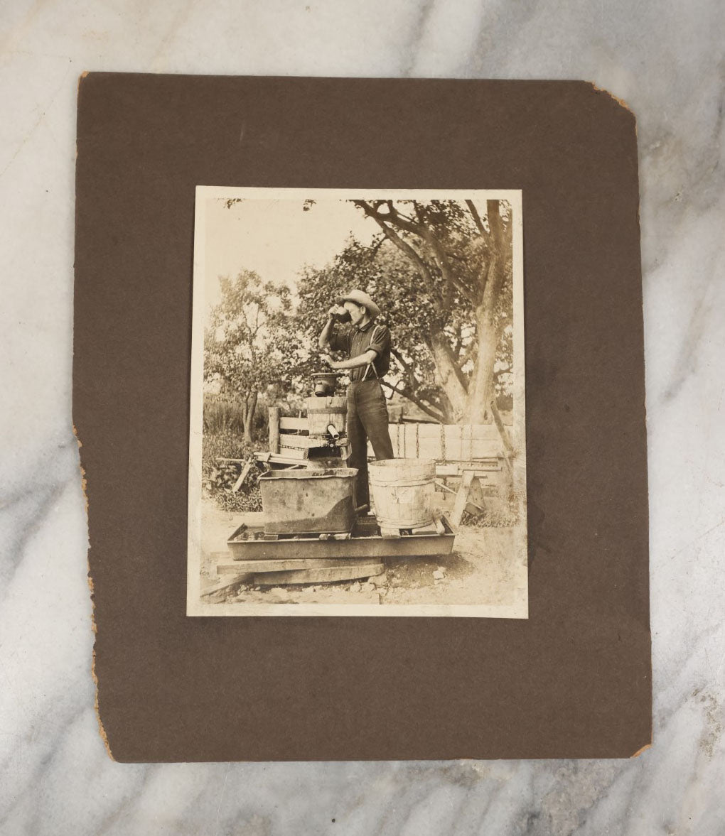 Lot 022 - Antique Boarded Occupational Photograph Of A Man Preparing A Beverage With A Press, Possible Moonshine Or Wine Making