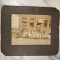 Lot 024 - Antique Boarded Occupational Photograph Of A Group Of Laborers Outside Of A Commercial Building, Note Ladies In Window, Striped Awnings