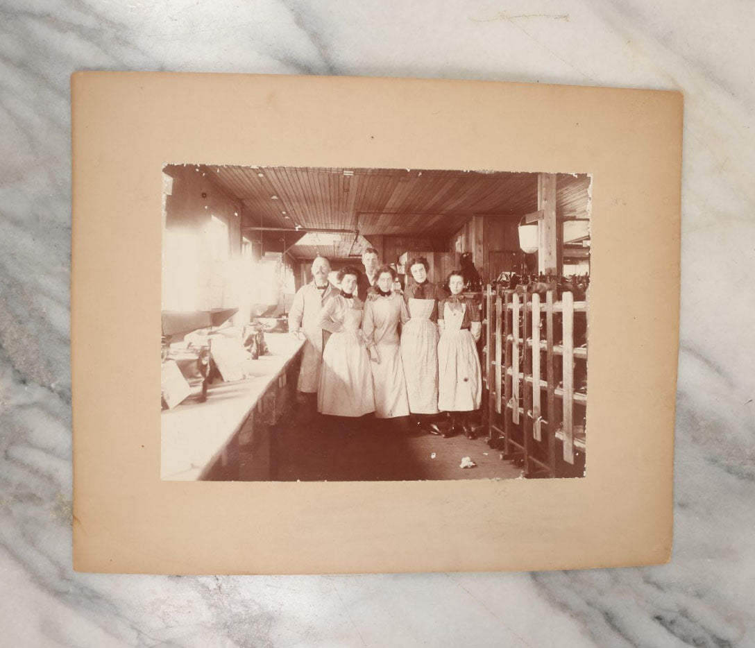 Lot 025 - Antique Boarded Occupational Photograph Of Four Women And Two Men Working In A Boot And Shoe Factory, Many Shoes Visible In Photo