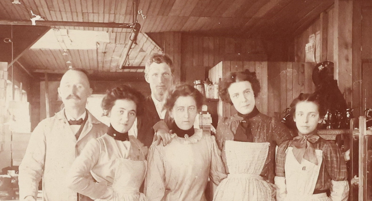 Lot 025 - Antique Boarded Occupational Photograph Of Four Women And Two Men Working In A Boot And Shoe Factory, Many Shoes Visible In Photo