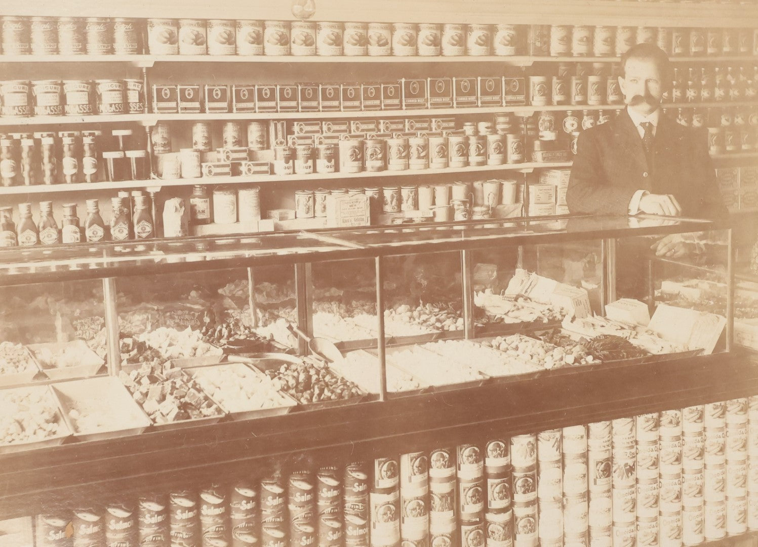 Lot 026 - Antique Boarded Occupational Photograph Of A Shopkeeper In A General Store, Identified As C.R. Johnson, 1907, Products Visible, Including Campbell's Soup Cans