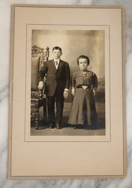 Lot 029 - Vintage Boarded Photograph Of A Young Couple With Dwarfism, Man And Woman, Well Dressed, Next To Ornate Chair