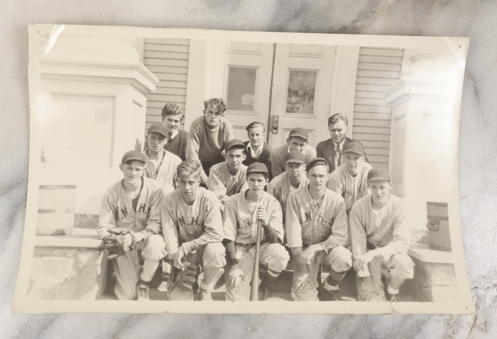 Lot 035 - Vintage Snapshot Photograph Of A Boys High School Baseball Team, Sitting On Front Stoop Of Building, With Coach