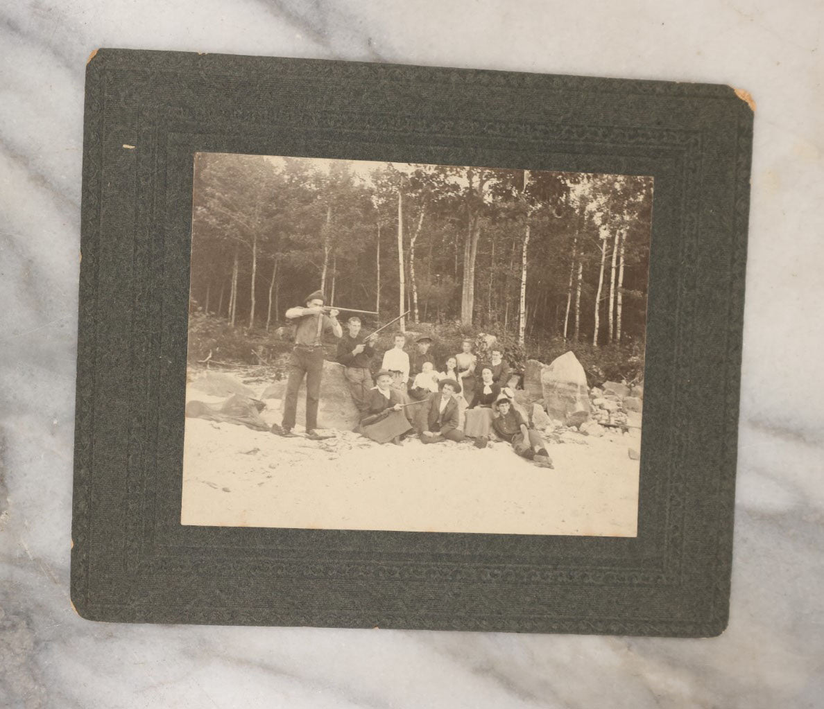 Lot 038 - Grouping Of Six Antique Boarded Photographs Related To Hunting And The Outdoors, Including Strung Up Deer, Group Photo With Man Shooting Rifle, Photo With People Holding Oars, Lake