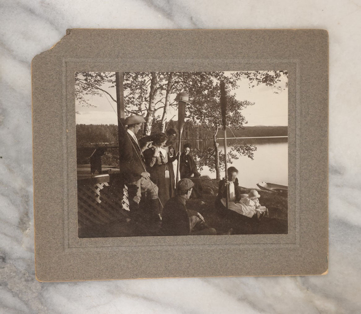 Lot 038 - Grouping Of Six Antique Boarded Photographs Related To Hunting And The Outdoors, Including Strung Up Deer, Group Photo With Man Shooting Rifle, Photo With People Holding Oars, Lake