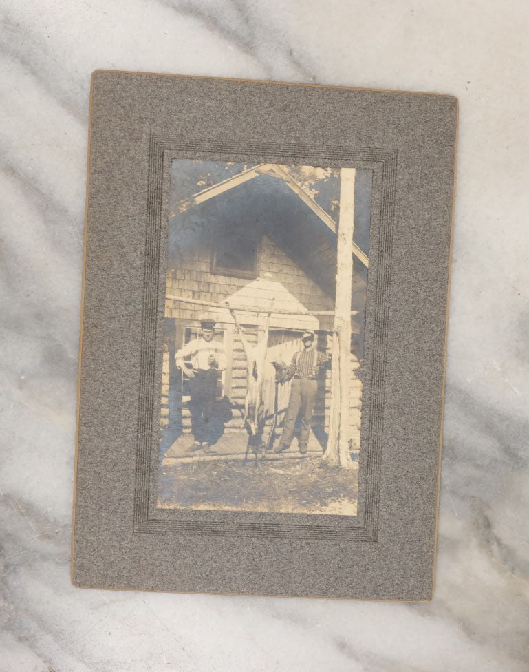 Lot 038 - Grouping Of Six Antique Boarded Photographs Related To Hunting And The Outdoors, Including Strung Up Deer, Group Photo With Man Shooting Rifle, Photo With People Holding Oars, Lake