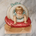 Lot 069 - Single Antique Die Cut Lithographed Scrap, Little Girl Crawling Through White Fur Muff