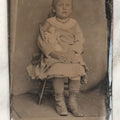Lot 019 - Single Antique Tintype Photograph Of A Little Girl Seated In A Small Wooden Chair With Her Doll Tucked Under Her Arm