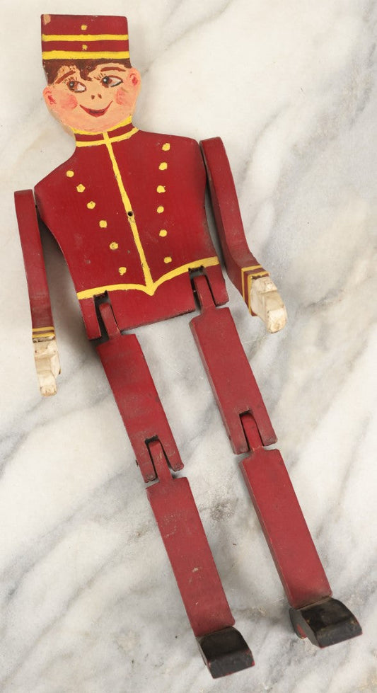 Lot 080 - Vintage Folk Art Wood Cut Bellhop Or Trainman Jointed Figurine, Hand Cut And Hand Painted, Red Clothes