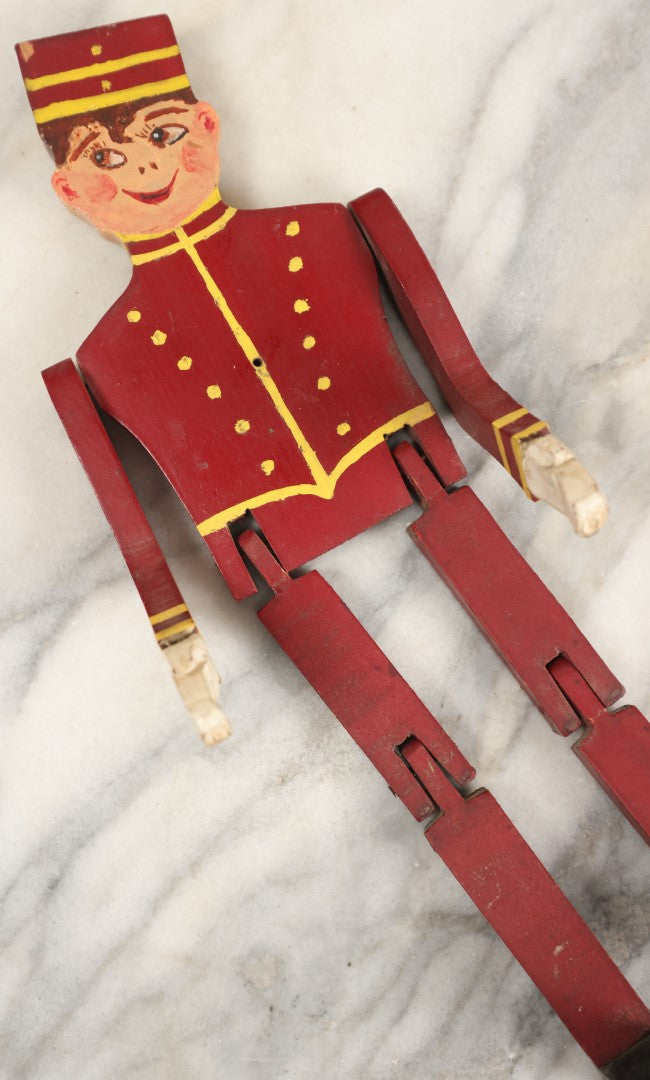 Lot 080 - Vintage Folk Art Wood Cut Bellhop Or Trainman Jointed Figurine, Hand Cut And Hand Painted, Red Clothes