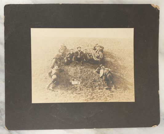 Lot 125 - Early Selfie, Antique Boarded Photograph Of A Group Of Men, Hikers, Forming An H On The Ground, With Hiker Flag On Grass, Note Man Left Center Pulling String To Operate The Shutter, Take Photo