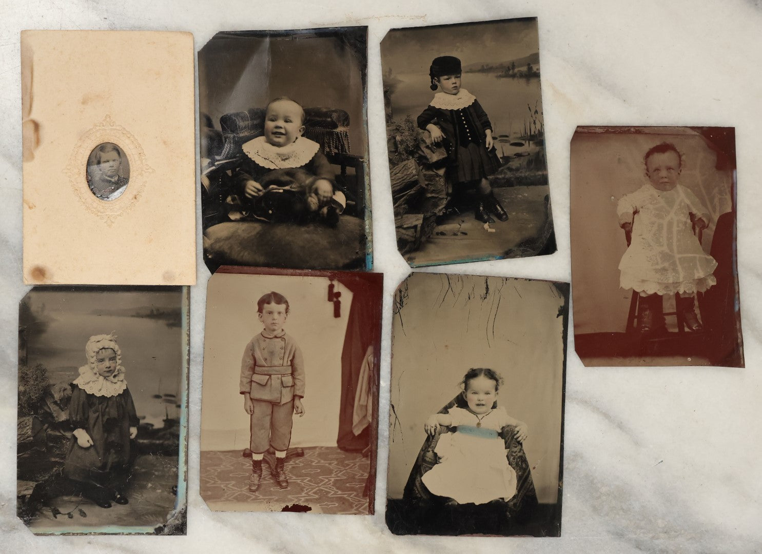 Lot 131 - Grouping Of Seven Antique Tintype Photographs Of Babies And Children, Including Smiling Baby With Tinted Yellow Waist Ribbon, Toddler In Winter Clothes With Gloves, And More