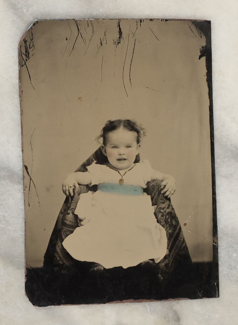 Lot 131 - Grouping Of Seven Antique Tintype Photographs Of Babies And Children, Including Smiling Baby With Tinted Yellow Waist Ribbon, Toddler In Winter Clothes With Gloves, And More