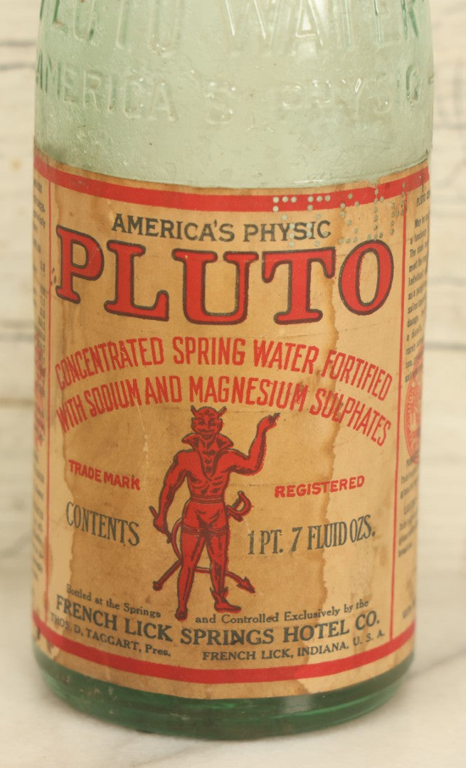 Lot 005 - Antique Pluto Water Glass Bottle With Original Paper Label, Devil Graphics, French Lick Springs Hotel Co., French Lick, Indiana, With Embossed Devil On Bottom, Drilled Cap