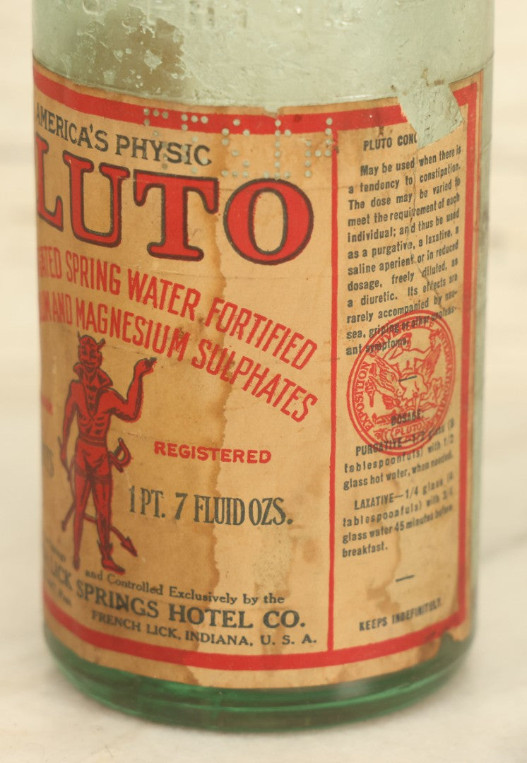 Lot 005 - Antique Pluto Water Glass Bottle With Original Paper Label, Devil Graphics, French Lick Springs Hotel Co., French Lick, Indiana, With Embossed Devil On Bottom, Drilled Cap