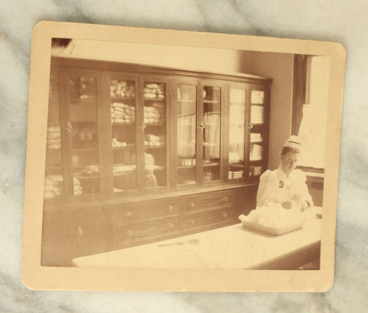 Lot 078 - Antique Boarded Occupational Photograph Of A Nurse At Work, Likely Boston City Hospital, 1899, Information On Verso