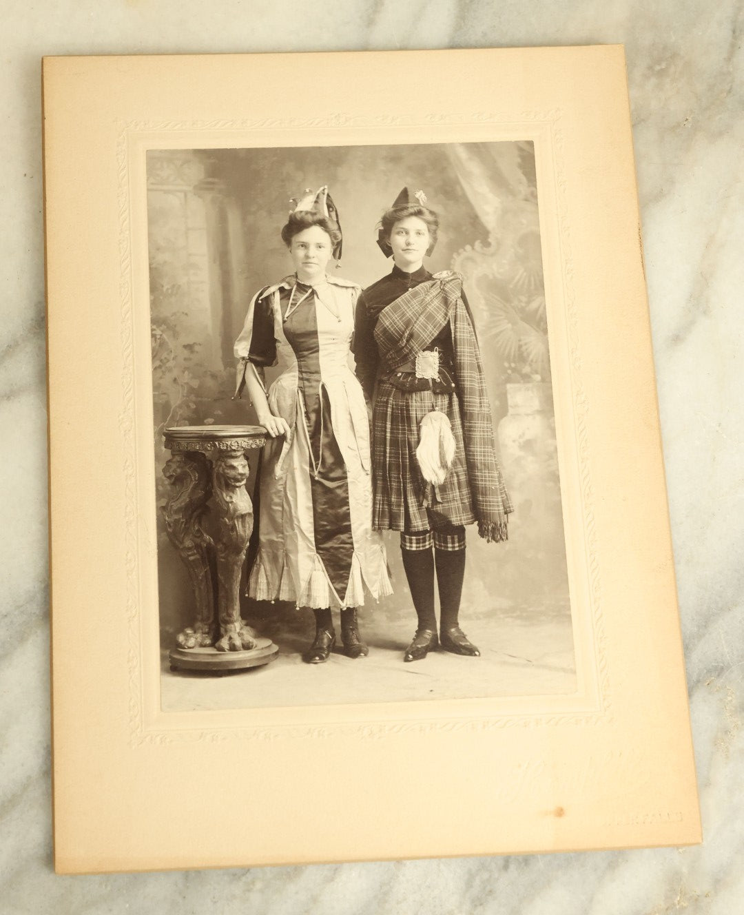 Lot 082 - Antique Boarded Photograph Of Two Young Women In Costume Standing Beside A Griffin Pedestal, Circa 1905