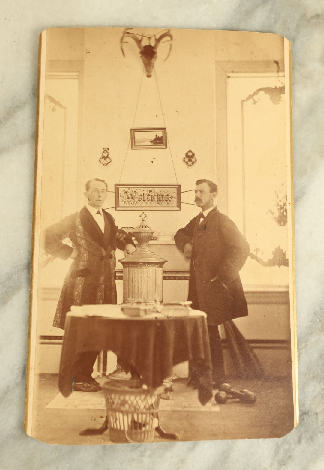 Lot 083 - Antique Interior Cabinet Card Photograph Of Two Men Standing In Front Of A Punchwork Embroidery, Taxidermy Deer Head, And More, Crosby, Photographer, Lewiston, Maine