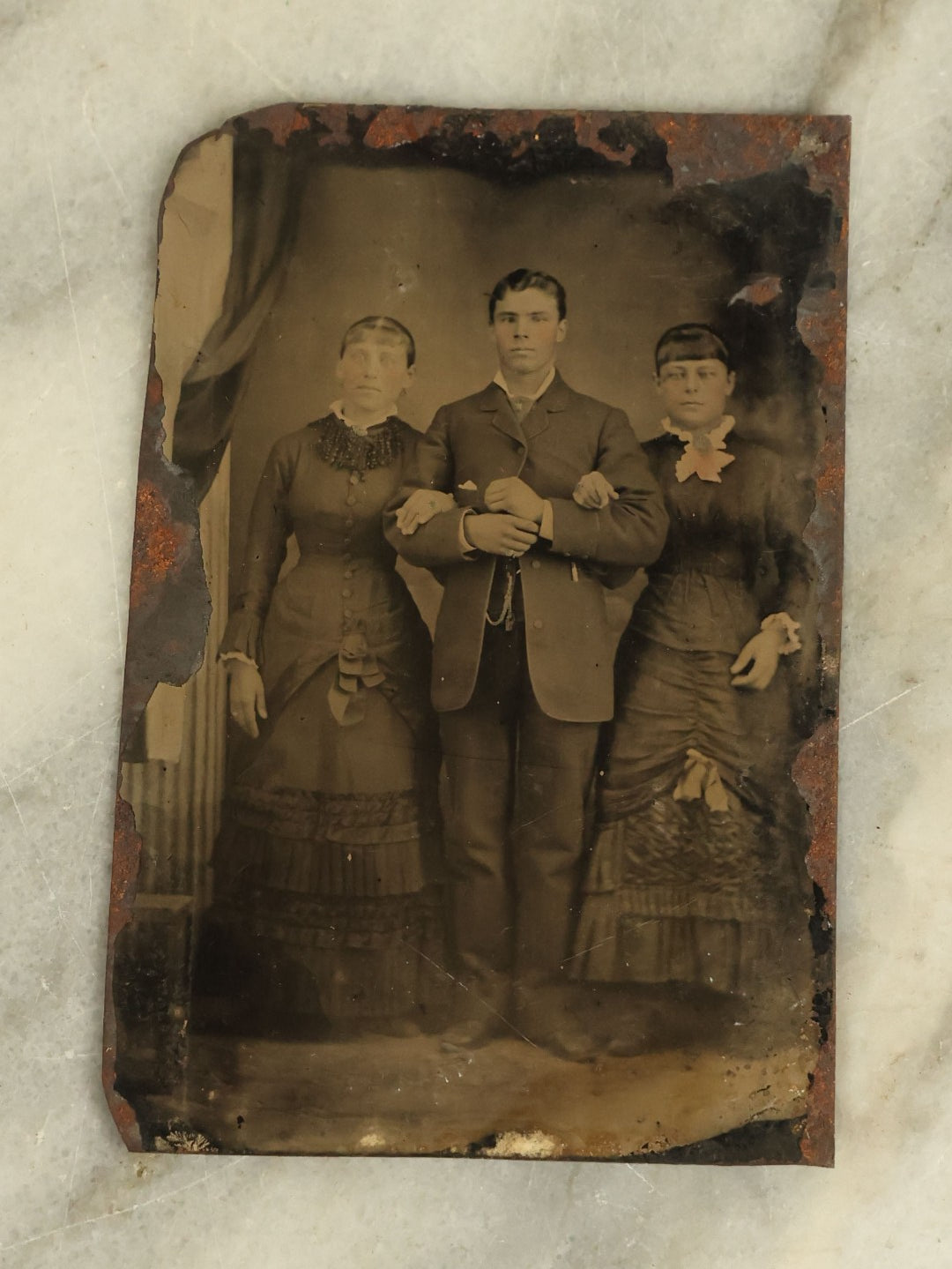 Lot 099 - Single Antique Tintype Photograph Of A Man Linking Arms With Two Ladies