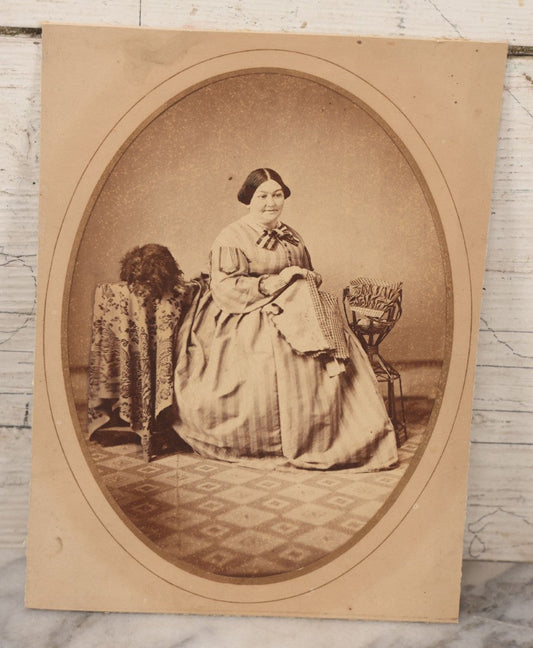 Lot 069 - Antique Matted Occupational Photograph Of An Adult Woman Seamstress, Pictured With Sewing Stand, And Scraggly Little Black Dog On Table To The Left, C.L. Obst Photographer, Pittsfield, Illinois