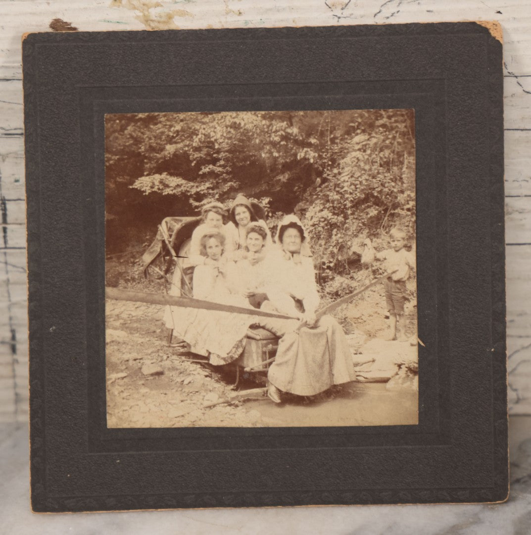 Lot 077 - Antique Boarded Photo Of Five Women In Makeshift Fanciful Flying Machine, Sleigh, Mother Hubbard Dress-Up, Little Boy In Background