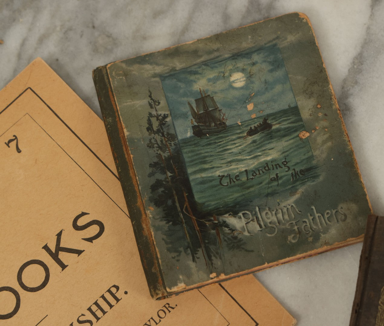 Lot 129 - Grouping Of Four Pieces Of Ephemera Including The Land Of The Pilgrim Fathers Book, Harper's Penmanship Book, Leather Blotter From Long Beach, California, And Infant Series Book