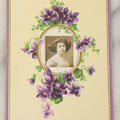 Lot 104 - Single Antique Postcard With Clipped Photo Of Young Woman With Large Bow, Purple Flower Design, Signed On Verso
