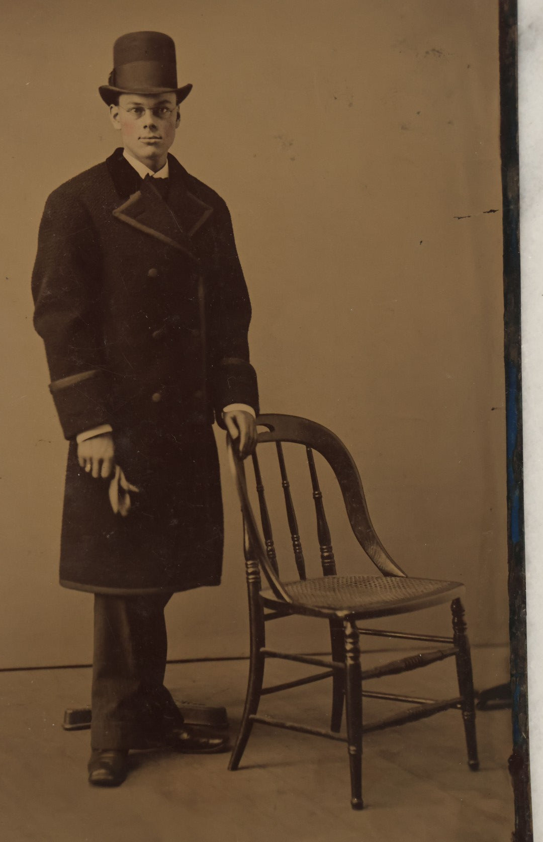Lot 110 - Approximately Half Plate Antique Tintype Photograph Of A Young Man Holding A Glove Wearing A Tall Bowler Hat, With Posing Stand In Frame, Chair