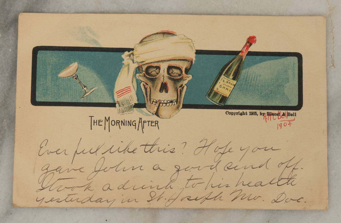 Lot 107 - Single Antique Postcard, "The Morning After" With Skull Smoking A Cigarette, Bottle Of Alcohol, Copyright 1905 By Blaesi & Bell, After A.M.C. Bell, 1904