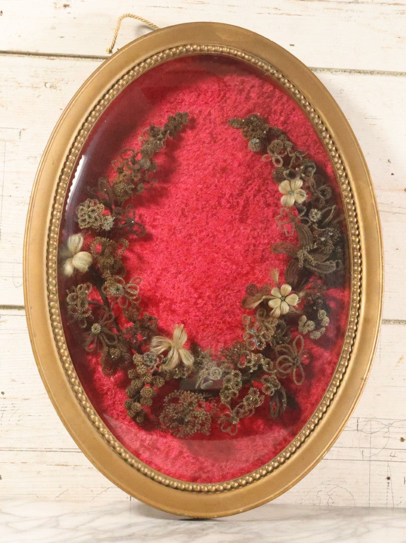 Lot 008 - Antique Victorian Human Hair Work Wreath In Oval Shadow Box With Bubble Glass, Refurbished Faux Red Velvet Back And Surround, 16" x 22"
