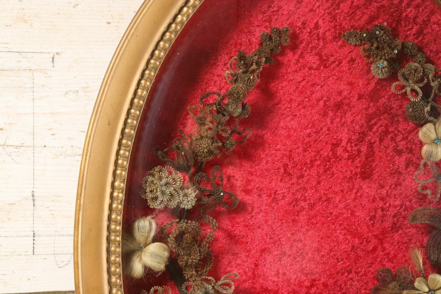 Lot 008 - Antique Victorian Human Hair Work Wreath In Oval Shadow Box With Bubble Glass, Refurbished Faux Red Velvet Back And Surround, 16" x 22"