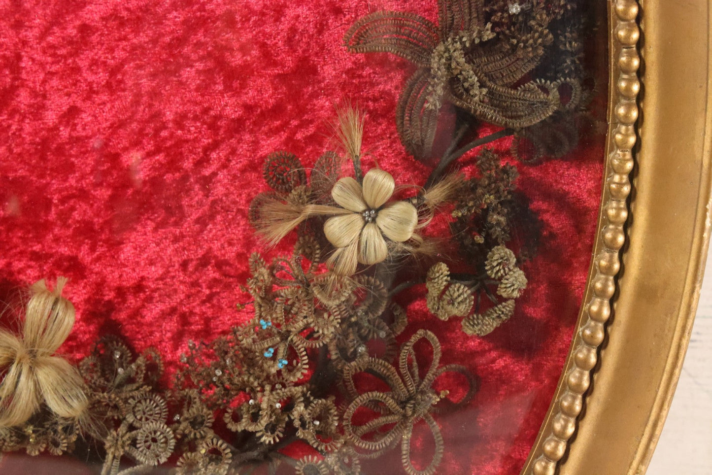 Lot 008 - Antique Victorian Human Hair Work Wreath In Oval Shadow Box With Bubble Glass, Refurbished Faux Red Velvet Back And Surround, 16" x 22"